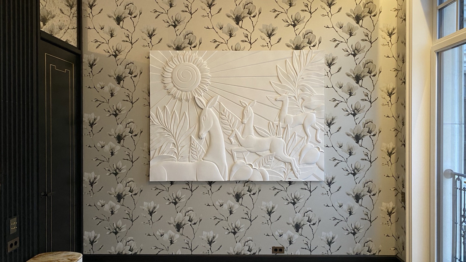 An Art Deco relief of leaping deer beneath a sun, installed on a patterned wall.