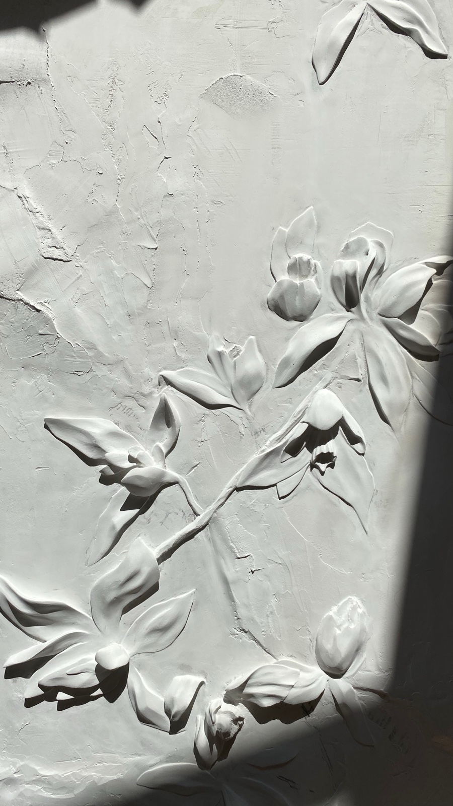 Close view of a white floral relief with deep cast shadows.