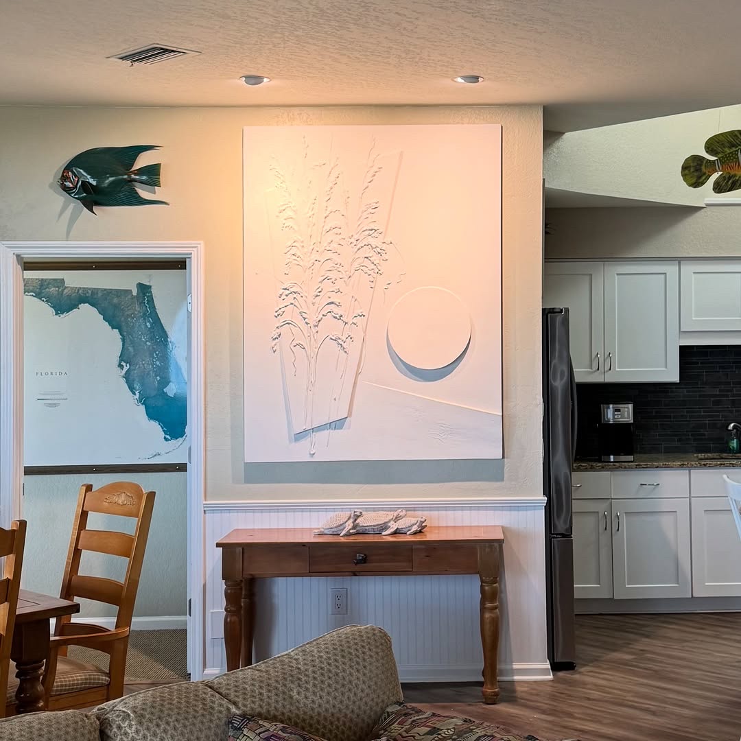 A relief panel of sea oats with a carved disc, installed above a console table.